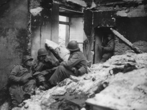 90th Infantry Division command team fights from a burned out house in Wiltz, Luxembourg during the Battle of the Bulge - January 1945. (U.S. Army Signal Corps Photo, Courtesy National Archives)