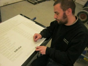 Engraver works on Garveston Twelve Memorial Stone, beginning with the name of lost airman, Pete DeBrular.